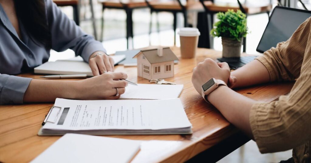 a real estate agent meeting with a customer, reviewing contracts