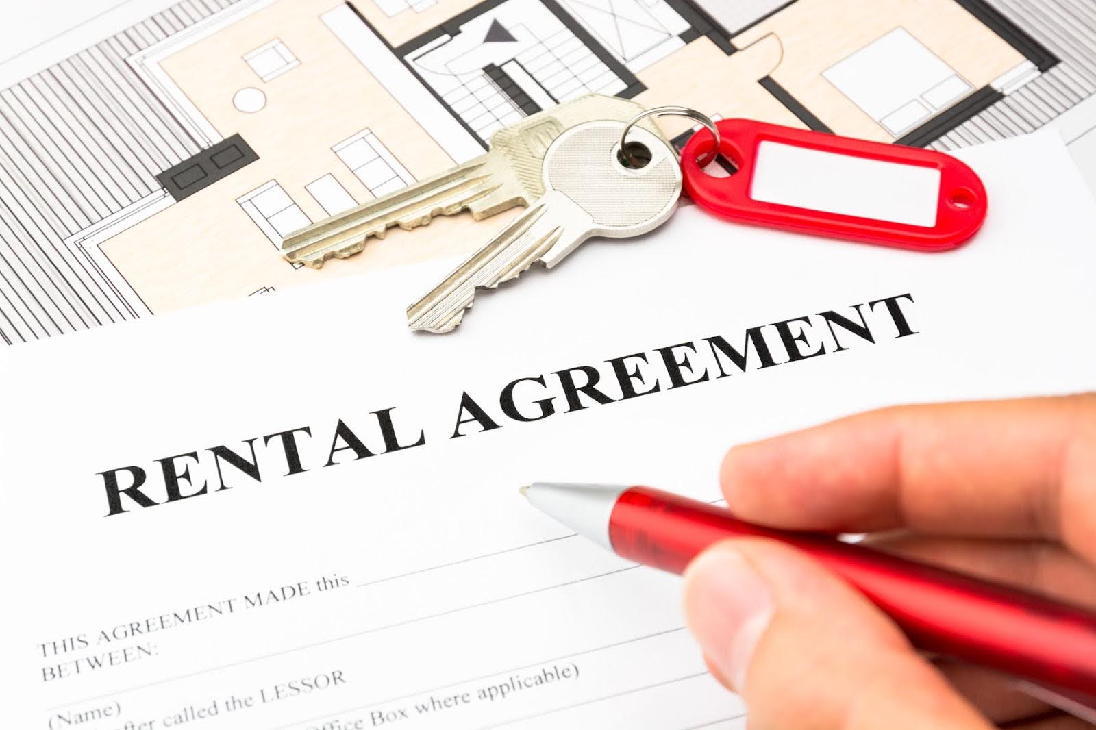 a rental agreement contract being signed with house keys in the background